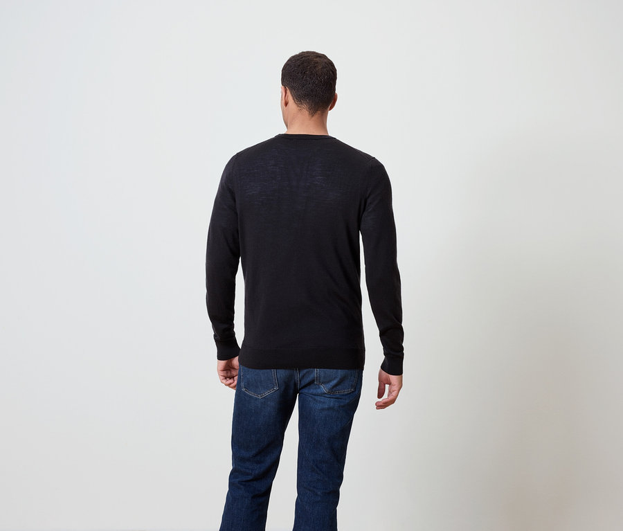 Muž zády, má na sobě tmavý svetr a džíny.