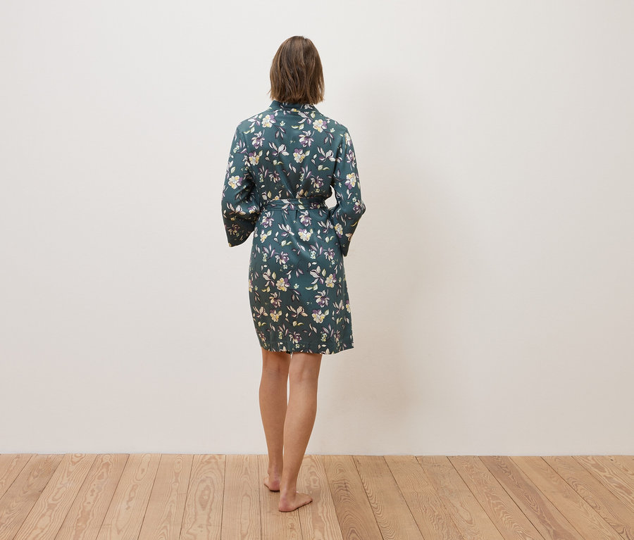 Žena stojí zády a má na sobě květinový župan.