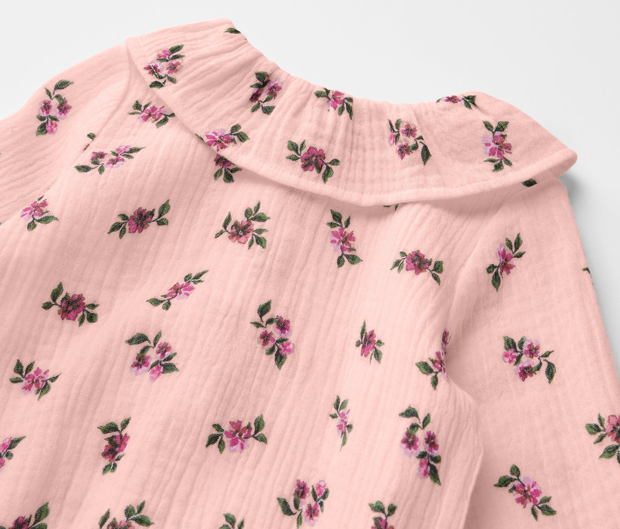 Detail mušelínového body pro miminka s květinovým vzorem.