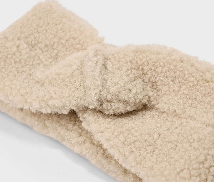 Detail béžové, zkroucené čelenky z plyše typu teddy.