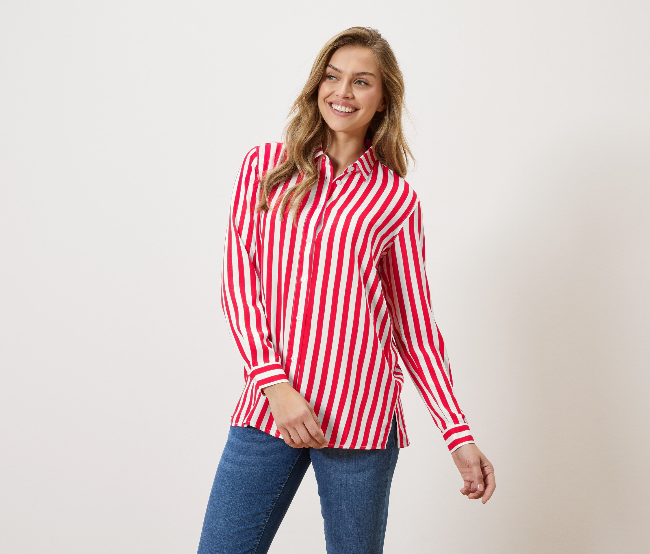Žena má na sobě červeno-bílou pruhovanou košili a džíny.
