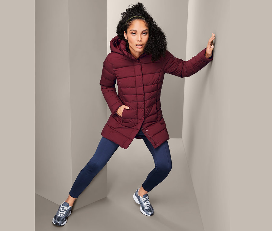 Žena pózuje v prošívaném kabátě.