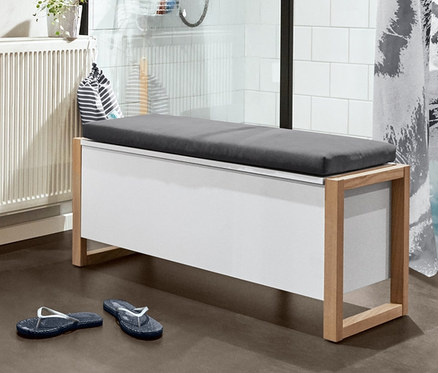 Interiér koupelny s vysokou skříňkou, skříňkou pod umyvadlo, regálem se 3 úložnými boxy, odkládacím vozíkem, hracím boxem s ptačím zpěvem, lavicí s polstrováním, sprchovým závěsem, tyrkysovou předložkou a žabkami.