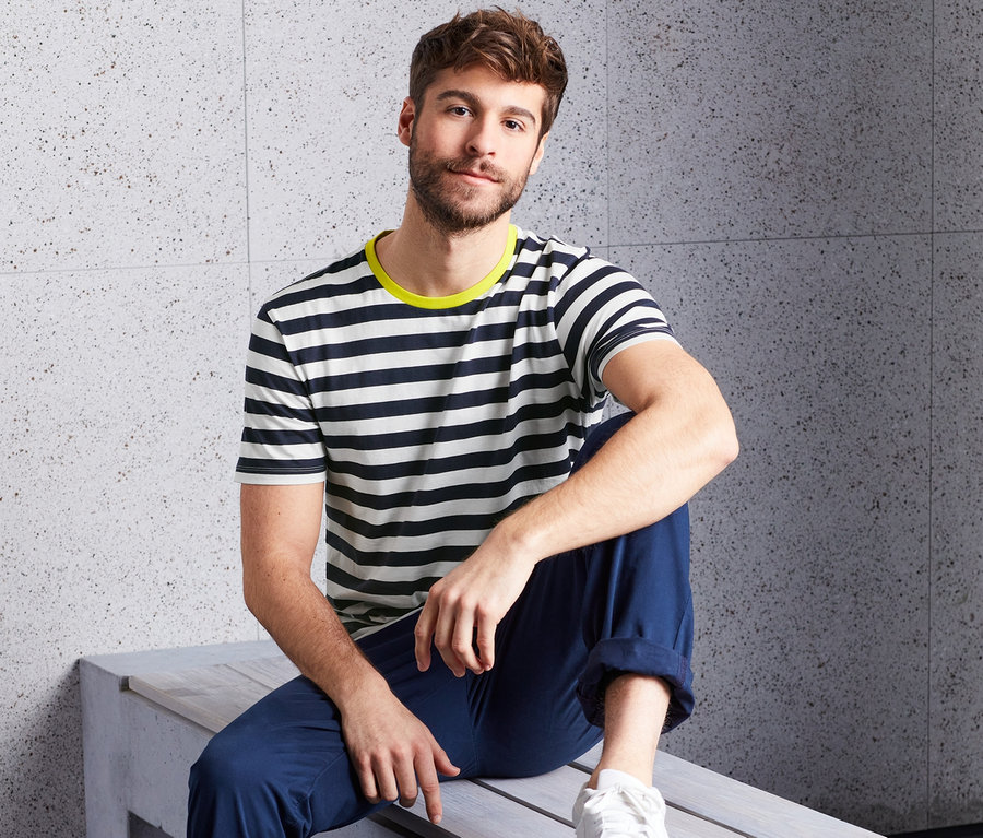 Muž sedí na lavičce a má na sobě tričko s kulatým výstřihem (2 ks) s námořnickými pruhy a žlutým lemem.