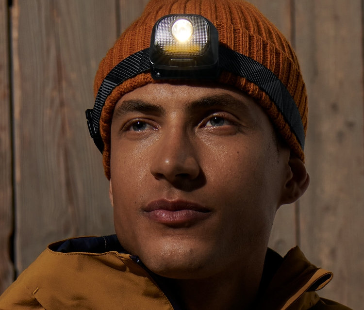 Muž má na sobě hnědou čepici a čelovku.