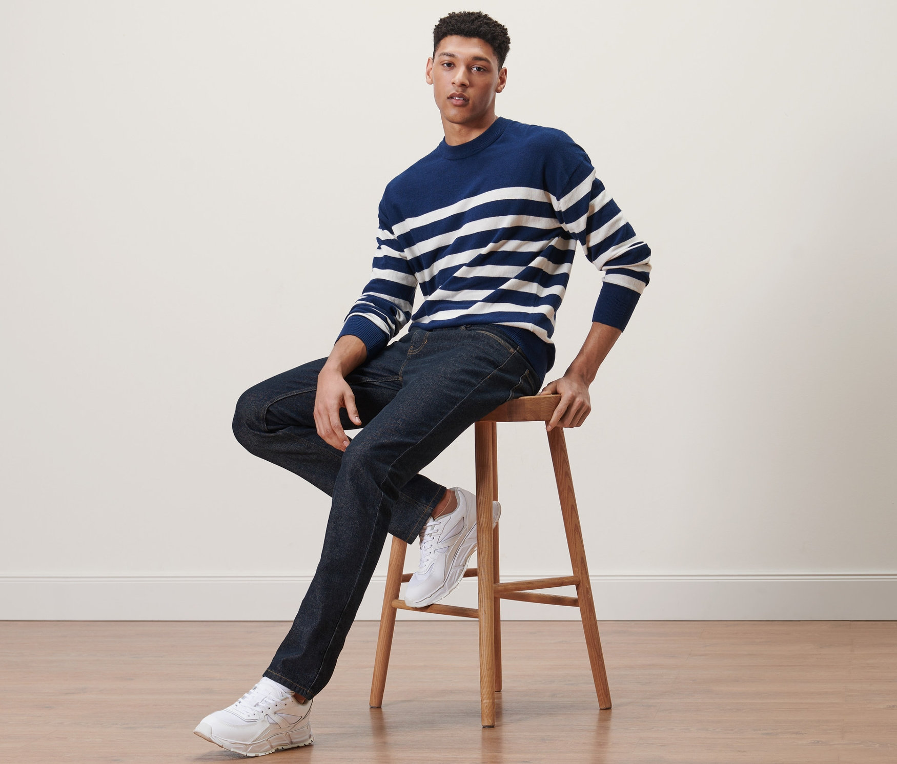 Muž sedí na stoličce a má na sobě džíny.