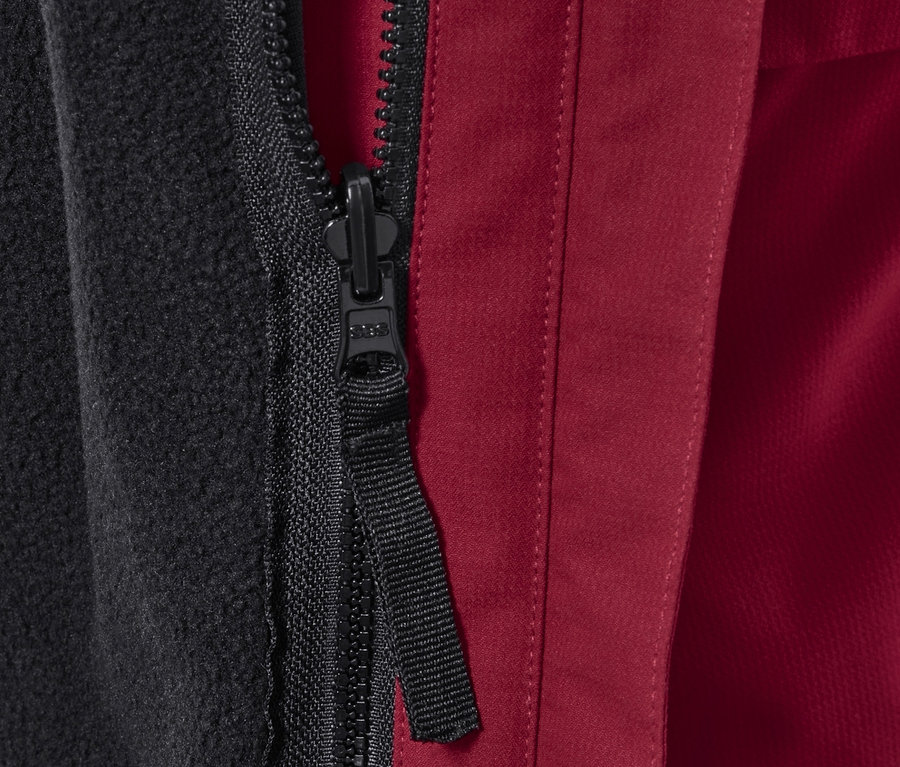 Detail zipu bundy s černou fleecovou podšívkou a červeným vnějším materiálem.
