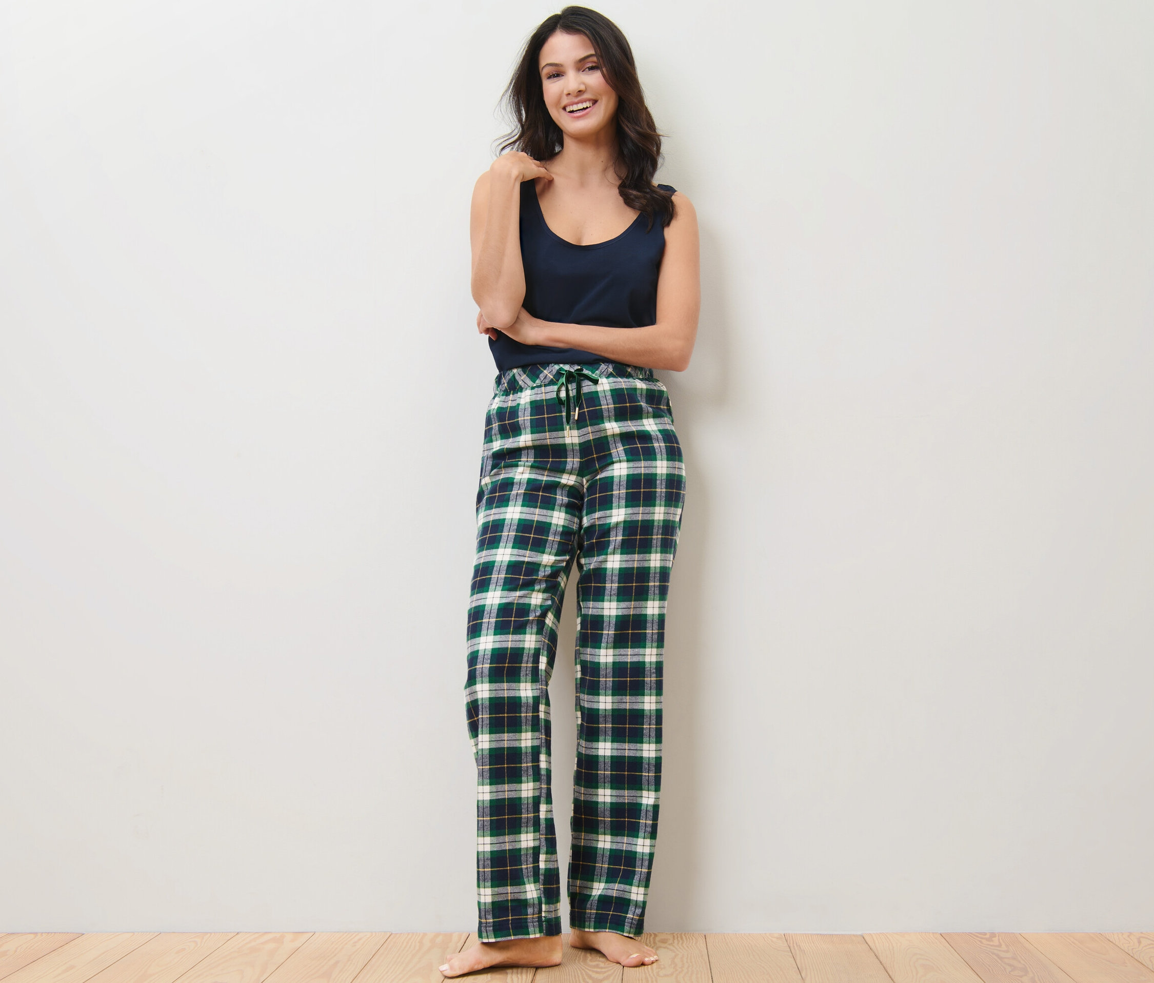 Žena stojí a pózuje v zelených flanelových kalhotách.