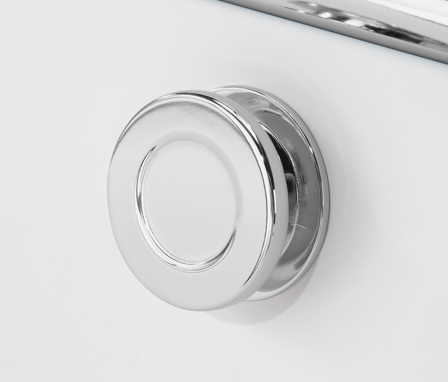 Detail bílé skříňky CN3 s chromovanou kulatou rukojetí a chromovanou tyčí nad ní.