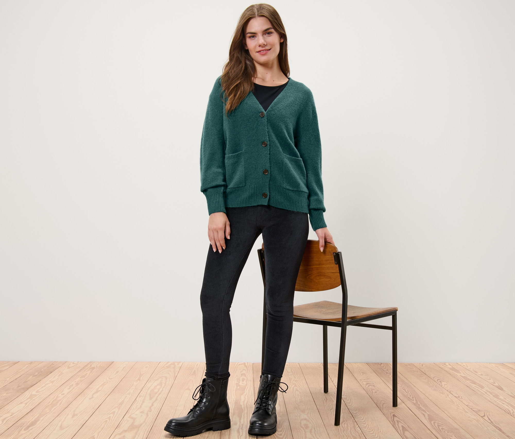 Žena stojí a má na sobě tmavě zelený pletený svetr s vlnou.