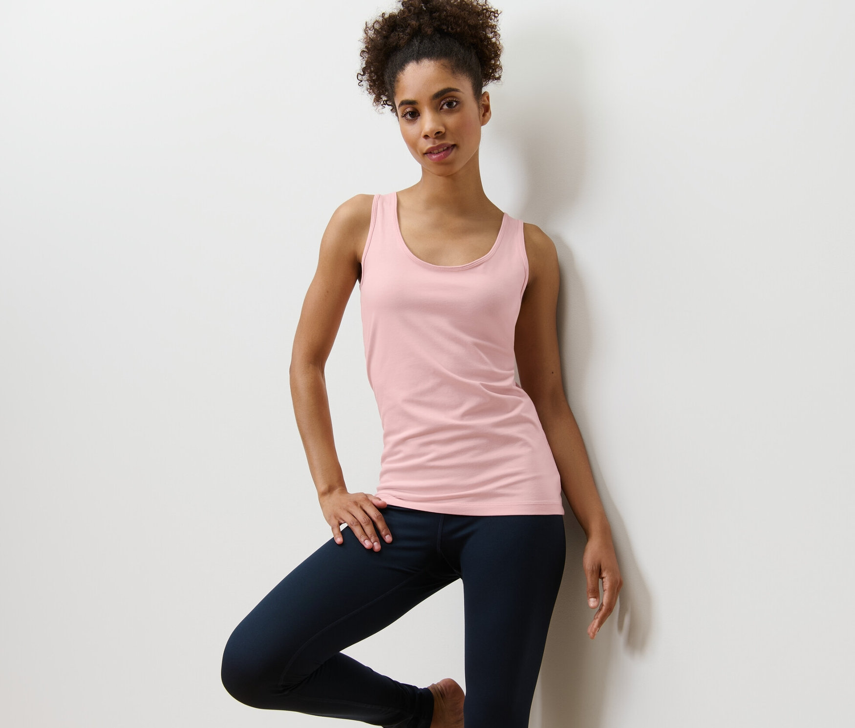 Žena pózuje v topu světle růžové barvy z dvoudílné sady topů.