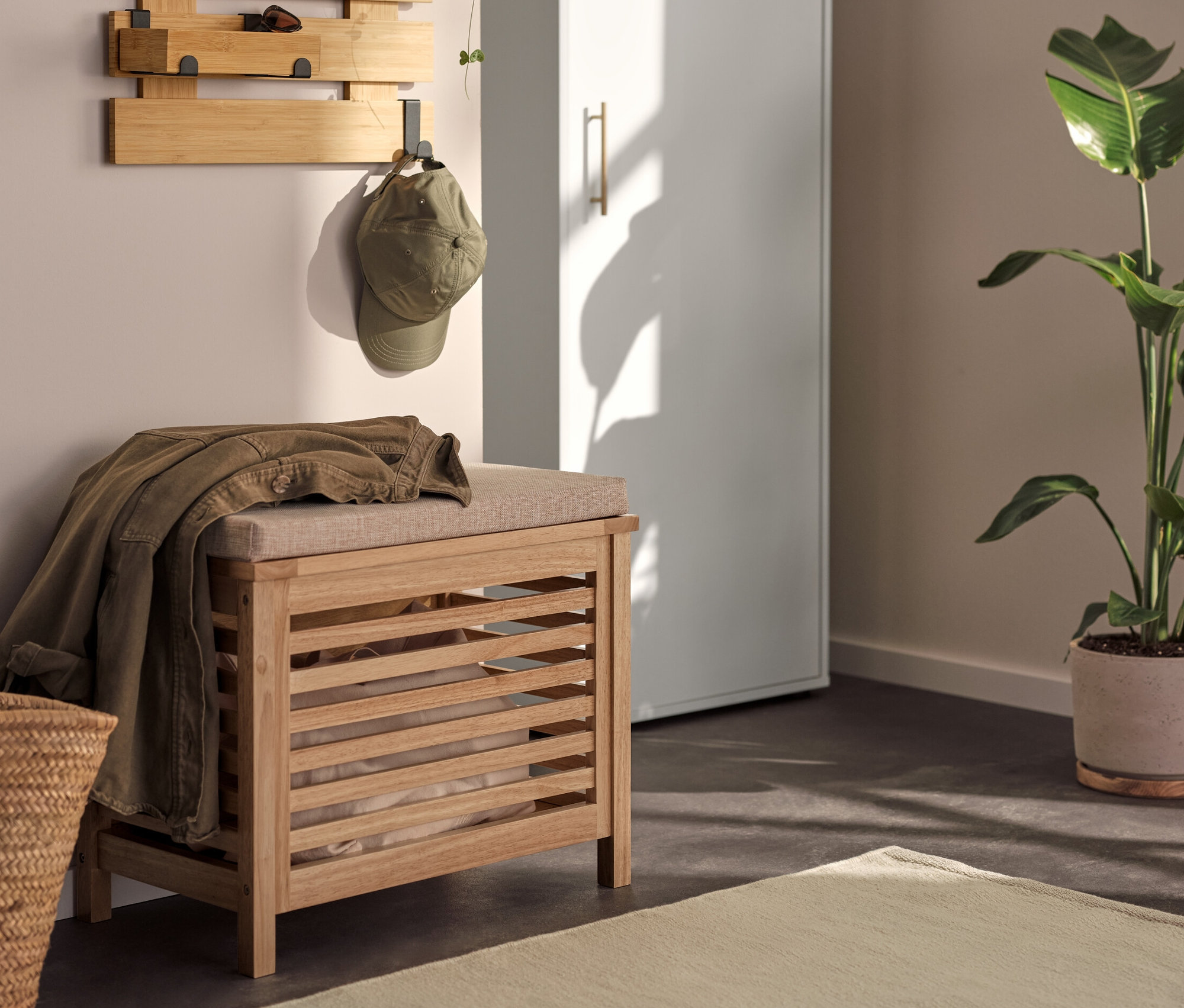 Interiér s univerzální skříní, nástěnným regálem s háčky, a sedací truhlou z masivního dřeva se sedákem.