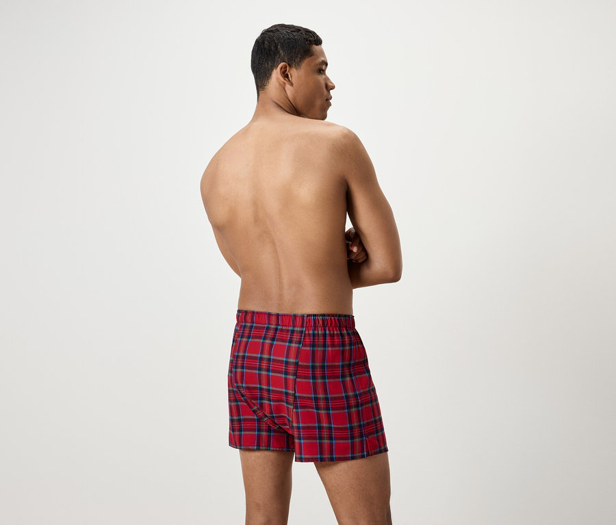 Muž zády ke kameře má na sobě červené kostkované trenýrky.