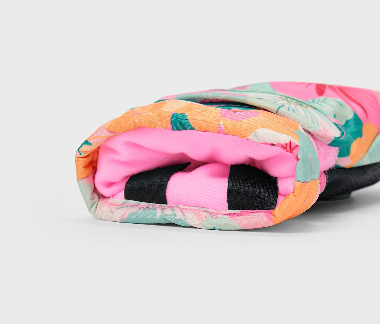 Detail pestrobarevného obalu s tropickým vzorem a růžovým vnitřkem.