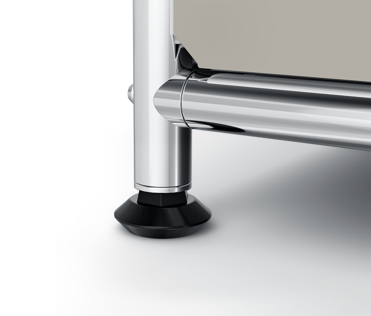 Detail chromované nohy a černého podstavce nábytku.