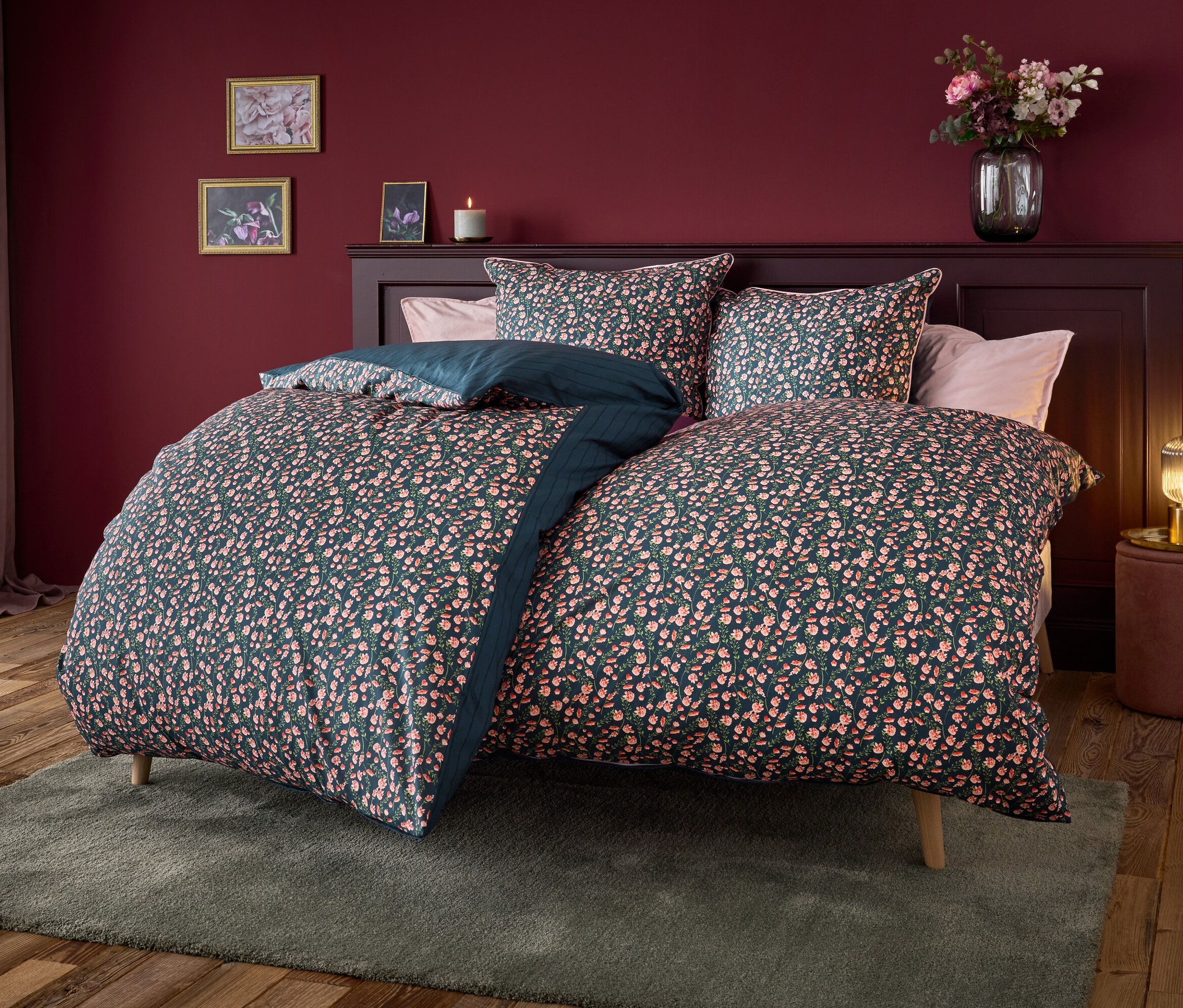 Postel s tmavě modrým povlečením s květinovým vzorem.