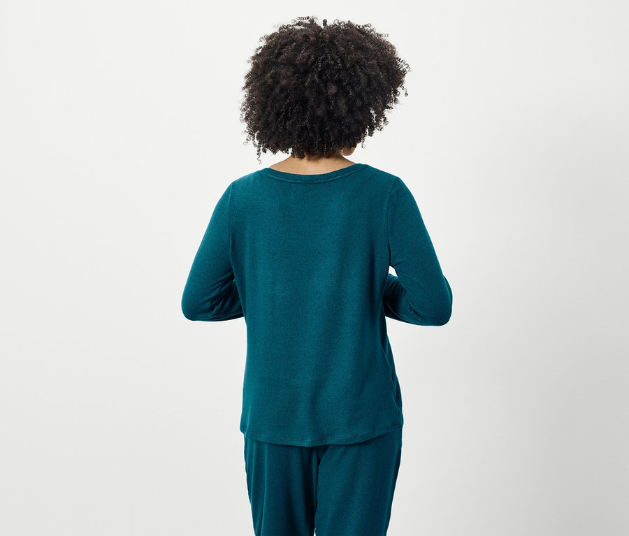 Zezadu pohled na ženu s afro účesem, oblečenou v tyrkysovém pyžamu s dlouhým rukávem a kalhotami.