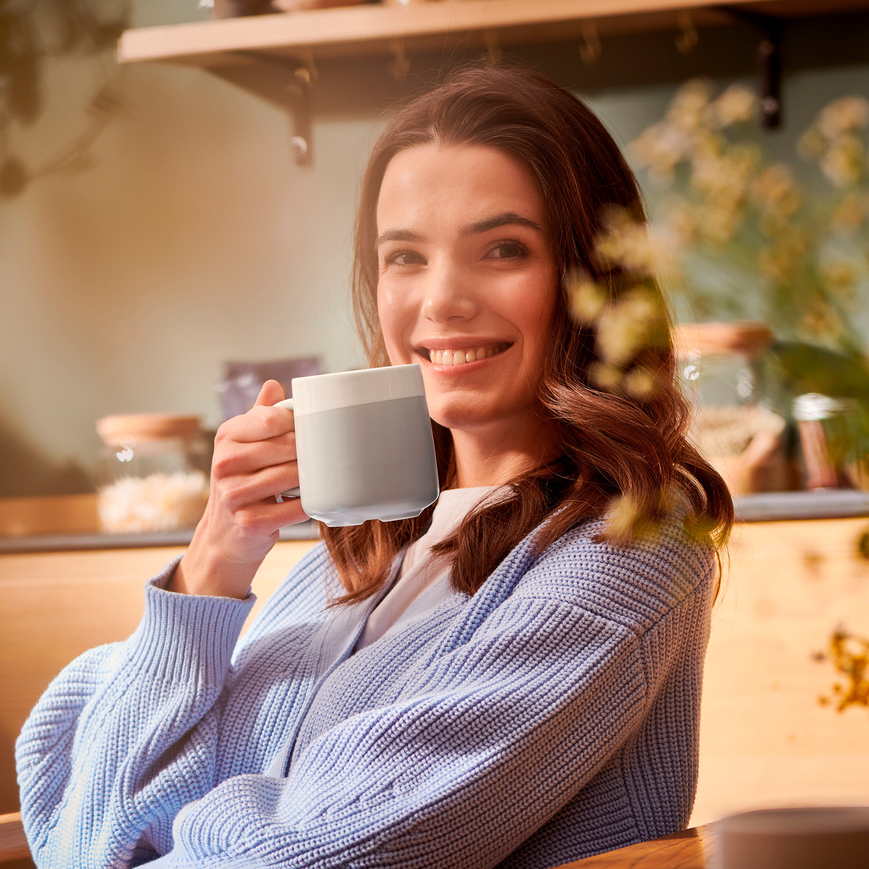 Usmívající se žena drží šedobílý hrnek.