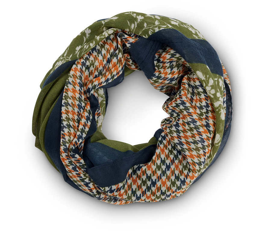 Detailní záběr na kruhový šátek s různými vzory, včetně květinových, kohoutí stopy a barevných bloků v odstínech zelené a modré.