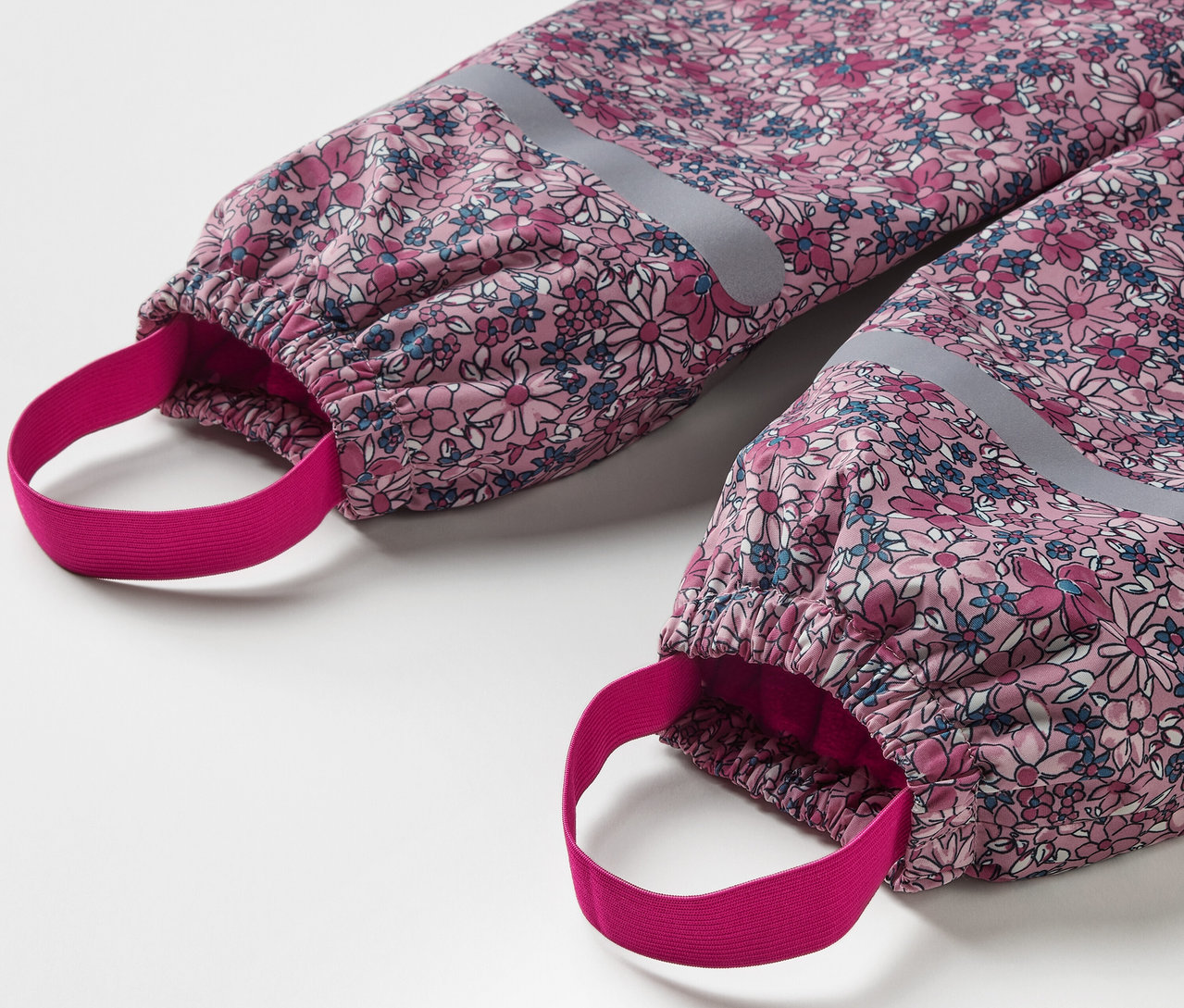 Detail dětských termo kalhot do deště s květinovým vzorem a reflexními prvky.