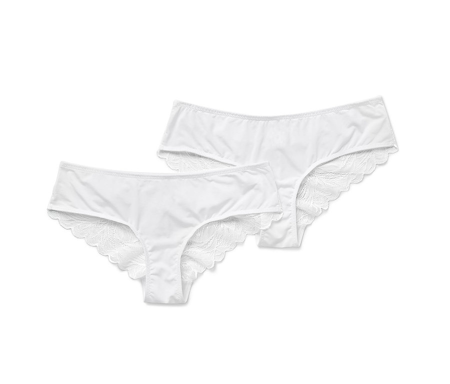 Dvoje bílé brazilské kalhotky s krajkou leží vedle sebe.