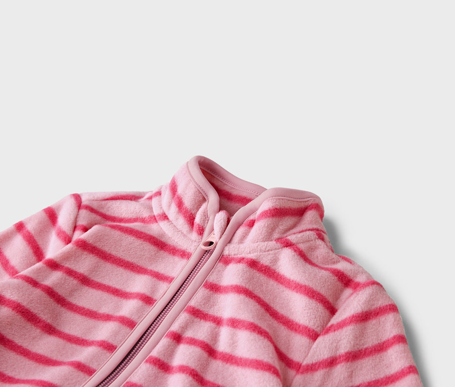 Detail růžové fleecové bundy s vodorovnými tmavě růžovými pruhy a zipem.