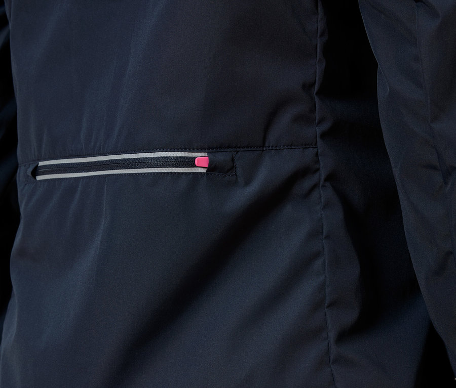 Detailní záběr na tmavě modrou bundu s kapsou na zip, jejíž zip má růžový akcent.