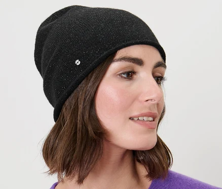 Žena s hnědými vlasy nosí černou třpytivou čepici beanie z jemného úpletu.