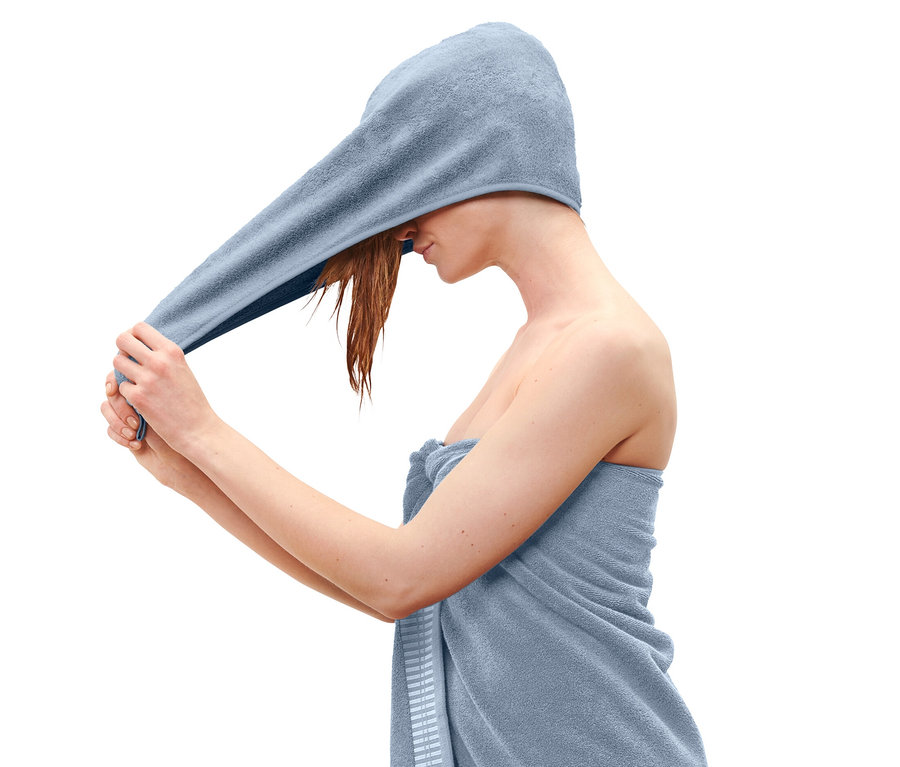 Žena si na hlavu dává světle modrý ručníkový turban.