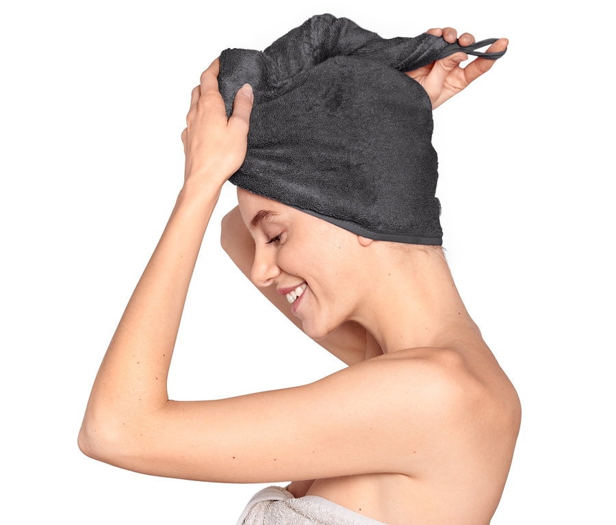 Žena si na hlavu nasazuje antracitový ručníkový turban.
