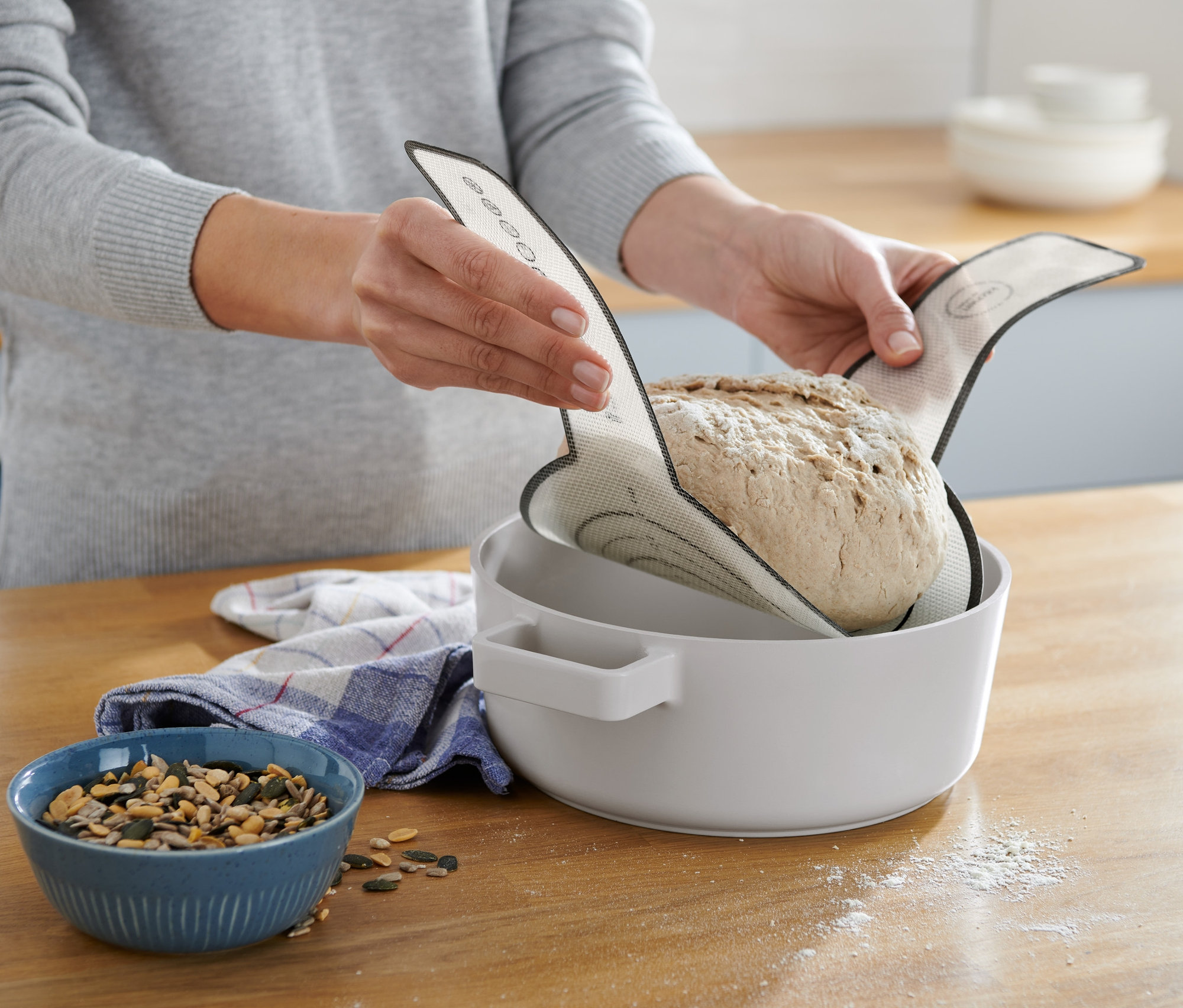 Žena vkládá chléb do mísy pomocí opakovaně použitelné podložky na pečení.
