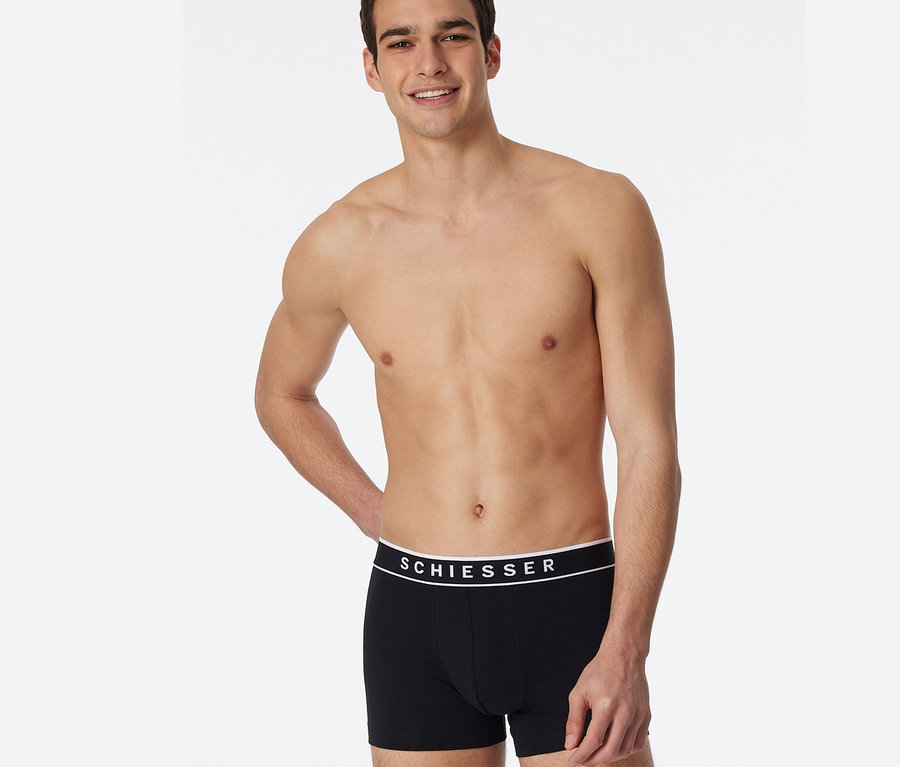 Muž pózuje v černých boxerkách SCHIESSER s bio bavlnou, 3 ks.