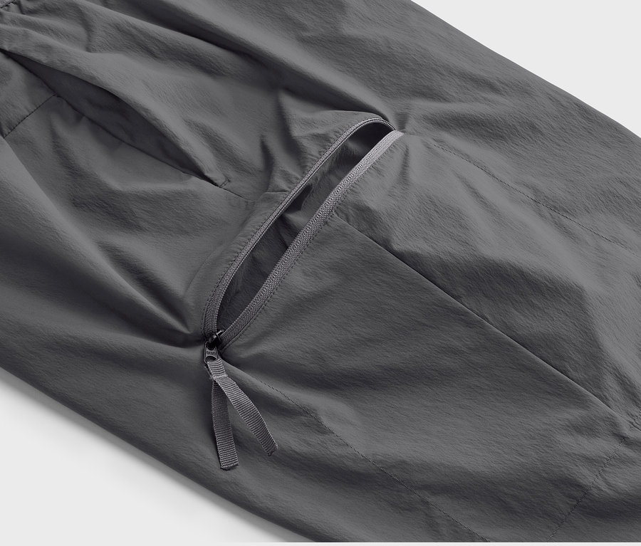 Detail šedých lehkých funkčních kalhot s kapsou na zip.