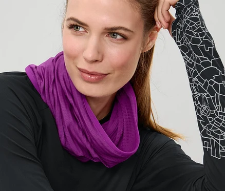Žena sedí a nosí fialový multifunkční šátek.