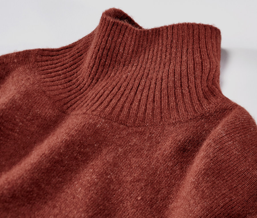 Detail hnědých pletených šatů s vlnou a rolákem.