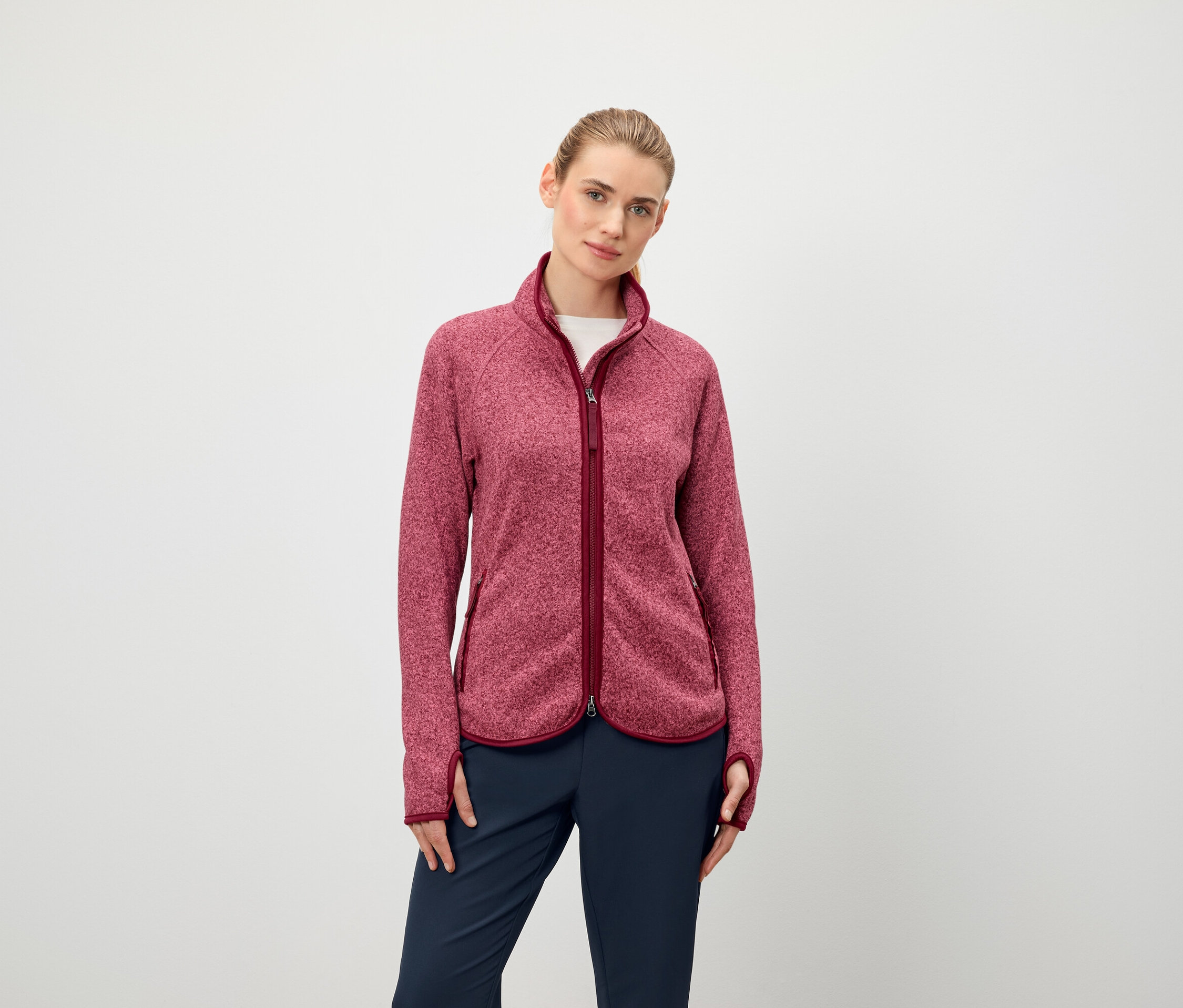 Žena má na sobě fleecovou bundu s dlouhým rukávem a zipem a tmavě modré kalhoty.