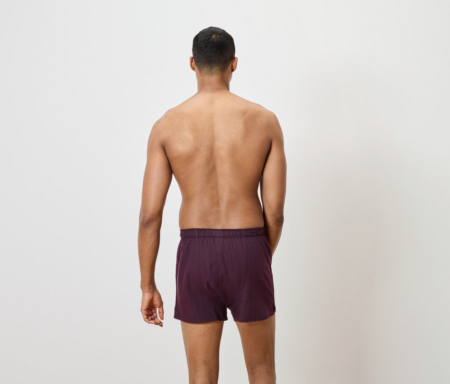 Zobrazena záda muže v bordových trenýrkách.