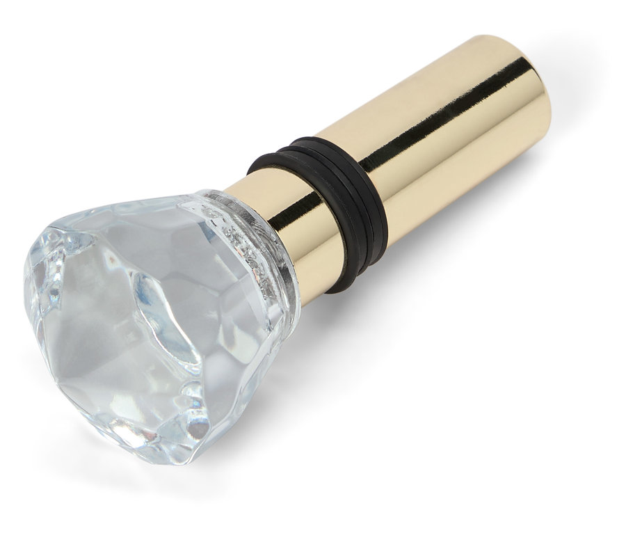 Zátka na láhev se skleněnou ozdobou ve tvaru diamantu a zlatou kovovou základnou.