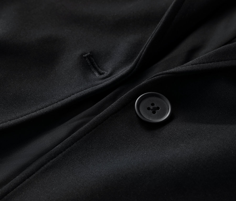 Detail černého žerzejového blejzru s knoflíkem.