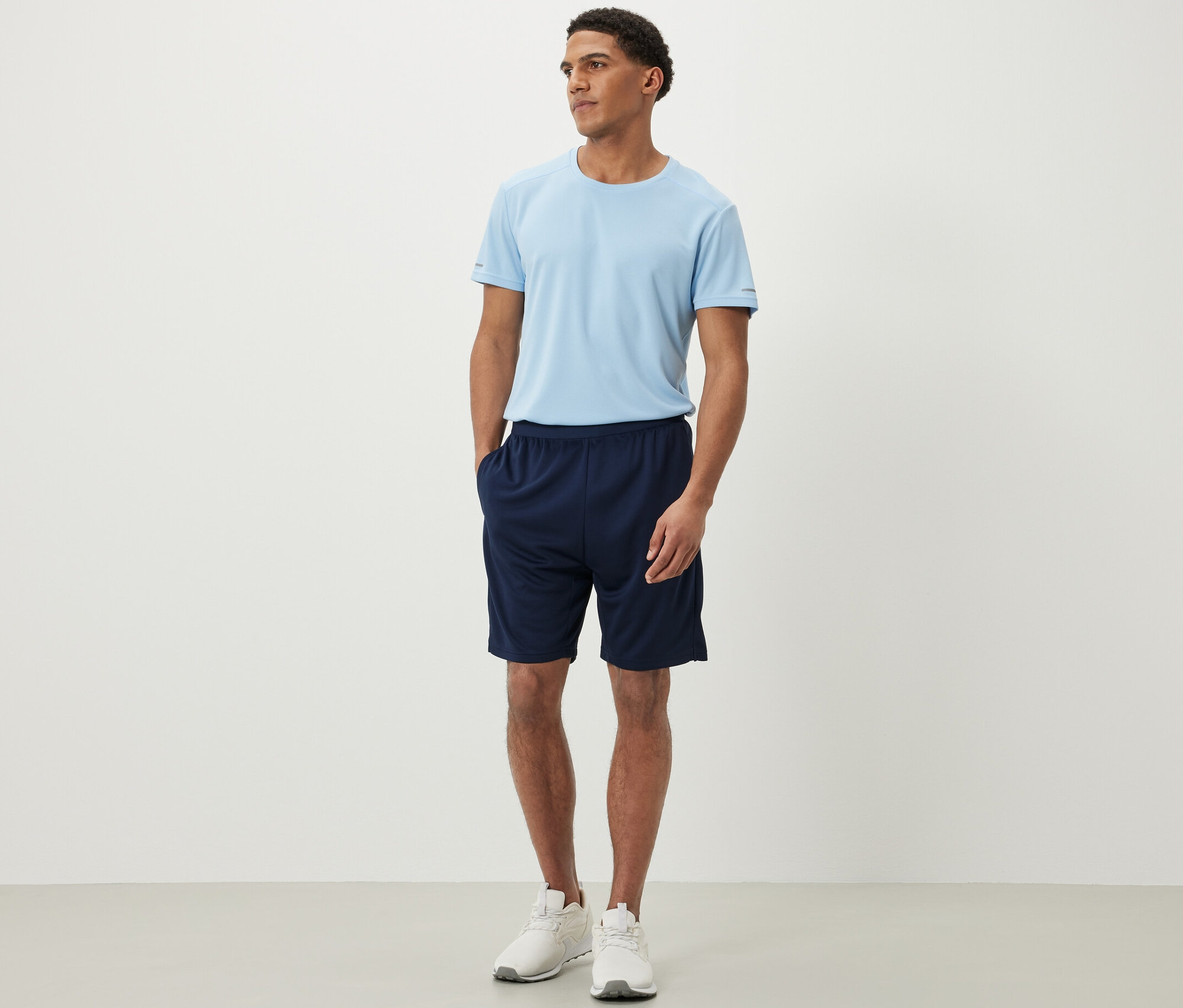 Muž stojí a má na sobě sportovní šortky a tričko.
