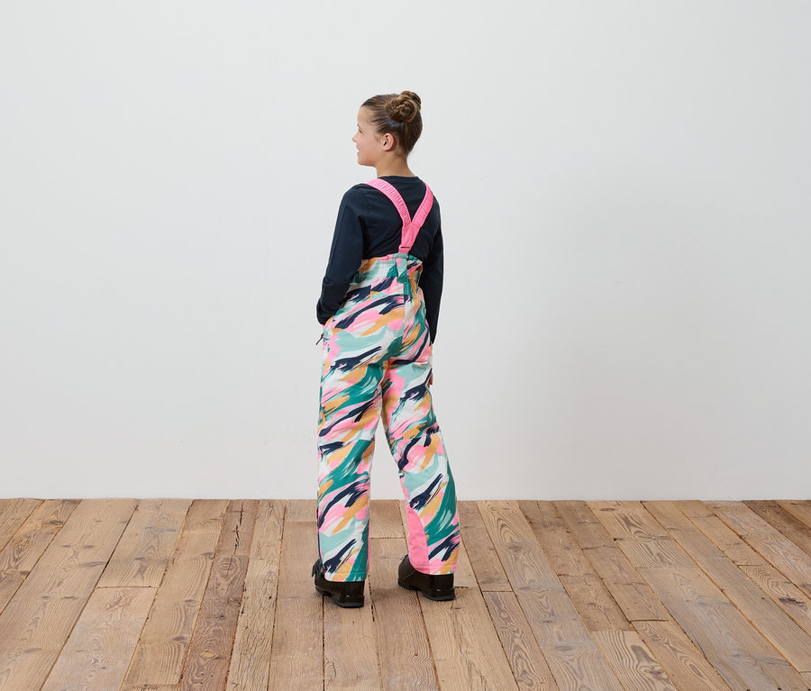 Dívka v lacláčích s barevným vzorem stojí zády ke kameře.