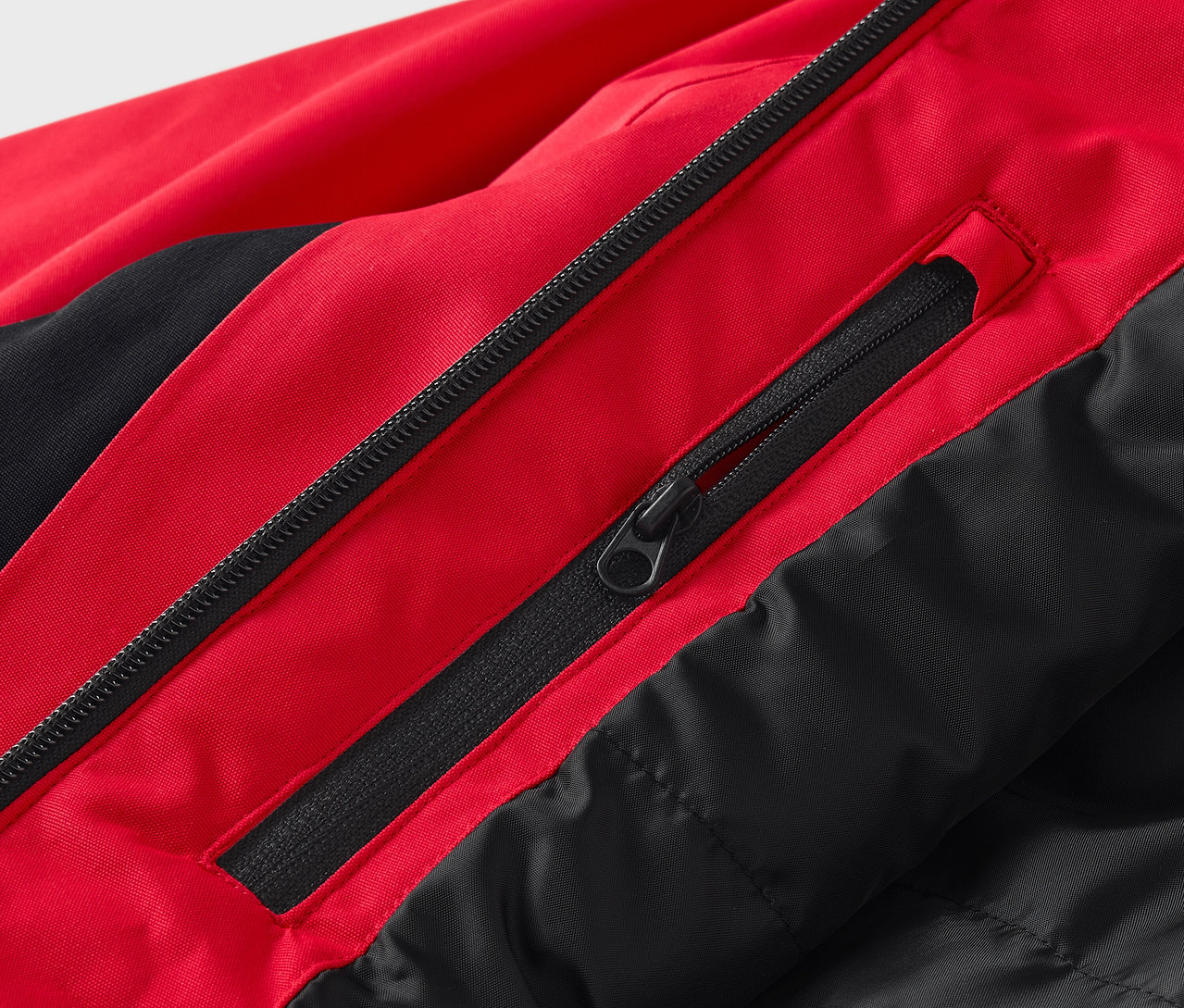 Detail červeno-černé bundy se zipy.