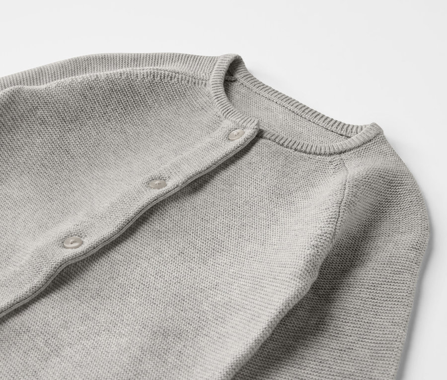 Detail šedého pleteného overalu pro miminka.