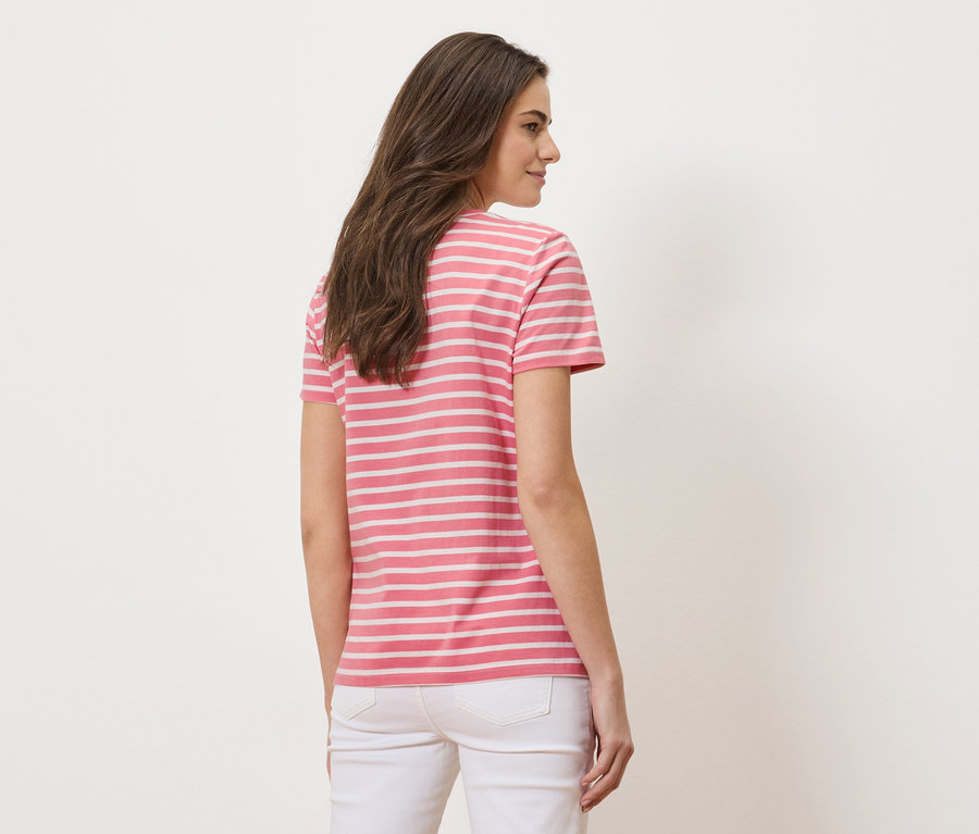 Žena zezadu, má na sobě růžovo-bílé pruhované tričko a bílé džíny.