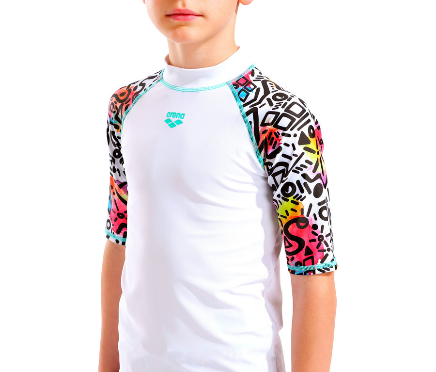 Detailní záběr na dítě v bílém plaveckém tričku Arena s barevnými geometrickými vzory na rukávech.
