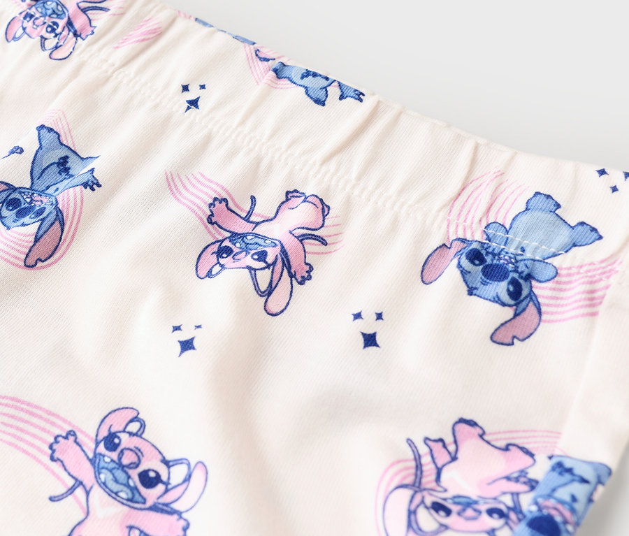 Detailní záběr na legíny s modrým a růžovým vzorem Stitch na béžové látce.