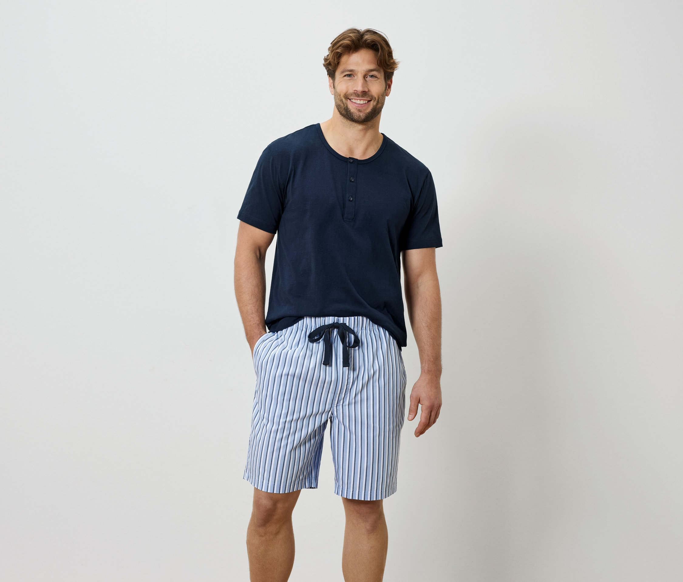 Muž v modrém tričku a pruhovaných šortkách.