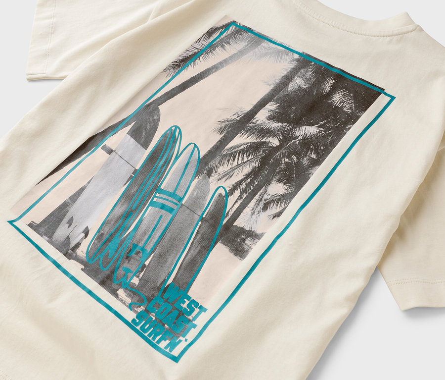 Na krémovém tričku je obdélník s potiskem palem a surfových prken.