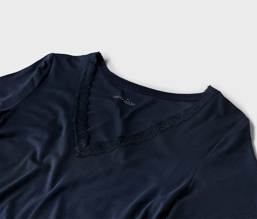 Detailní záběr na tmavě modré tričko s výstřihem do V a krajkovými detaily.