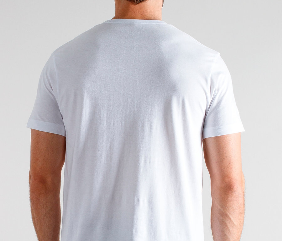 Pohled zezadu na muže v bílém tričku a kostkovaných pyžamových kalhotách na neutrálním pozadí.